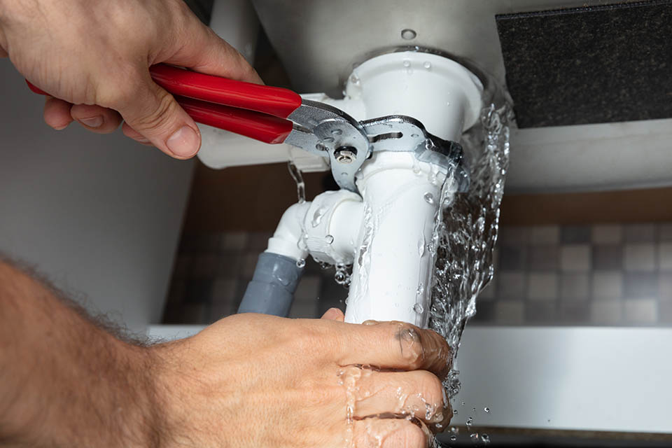 Plumber Fixing Sink Pipe With Adjustable Wrench
